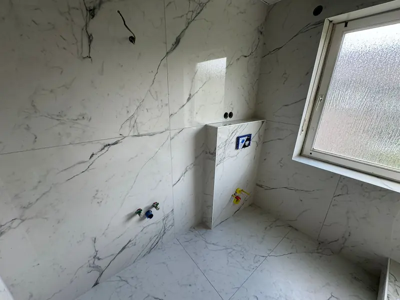 Badezimmer mit Wand- und Bodenfliesen in Marmoroptik