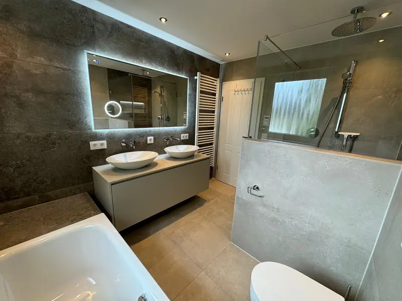 Badezimmer mit Doppelwaschtisch, Aufsatzbecken und Wandfliesen in Natursteinoptik