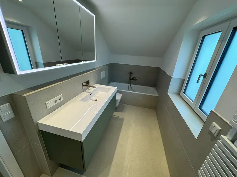 Modernes Badezimmer mit großformatigen Fliesen, Waschtisch und LED-Spiegelschrank