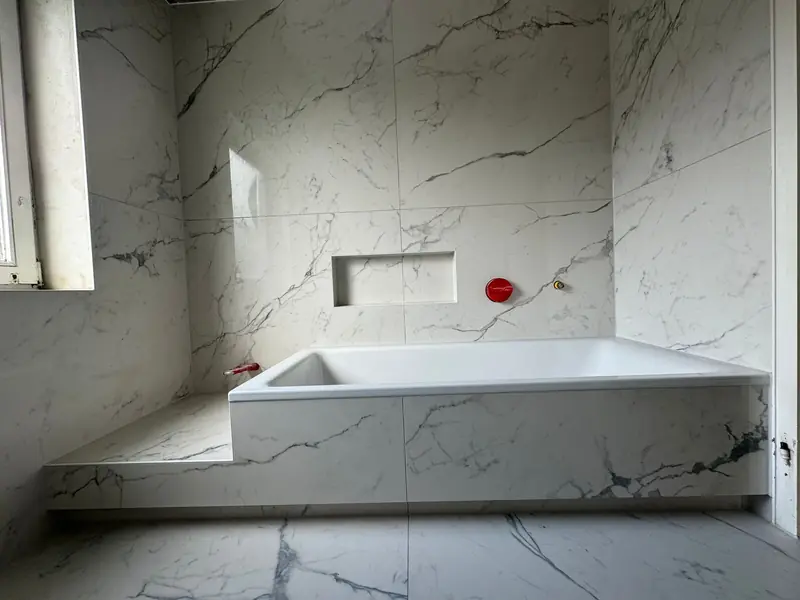 Badezimmer mit großformatigen Marmor-Fliesen und eingefliester Badewanne