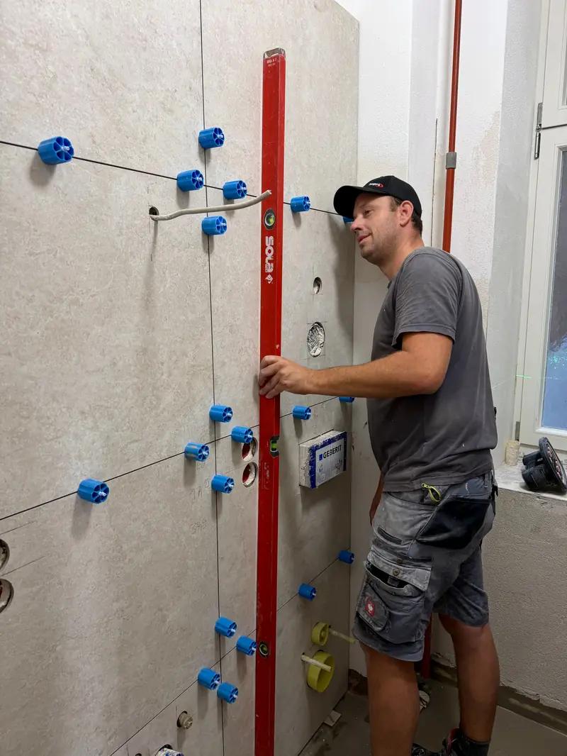Fliesenleger richtet eine Wandfläche mit der Wasserwaage aus