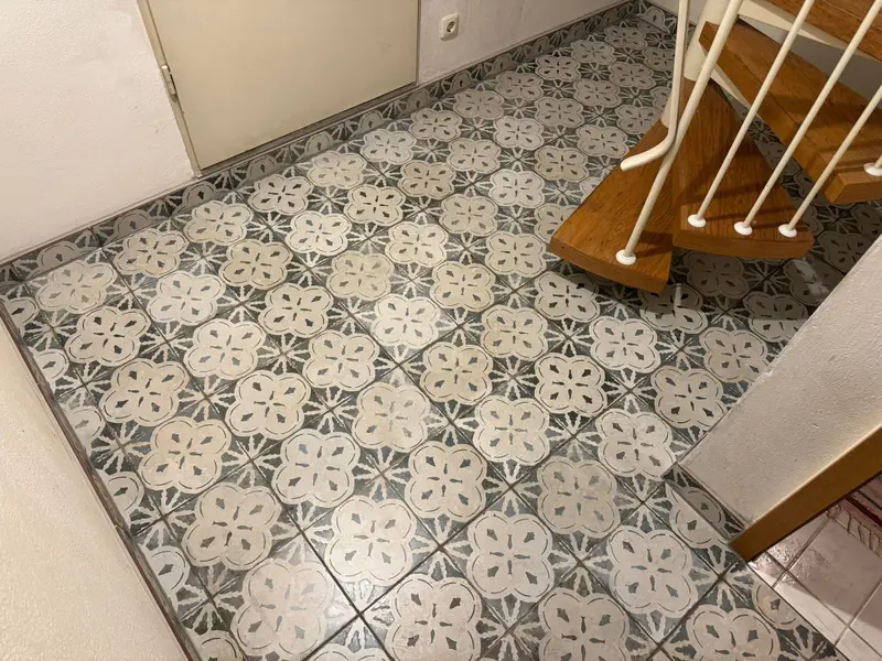 Flur mit gemusterten Fliesen neben einer Holztreppe