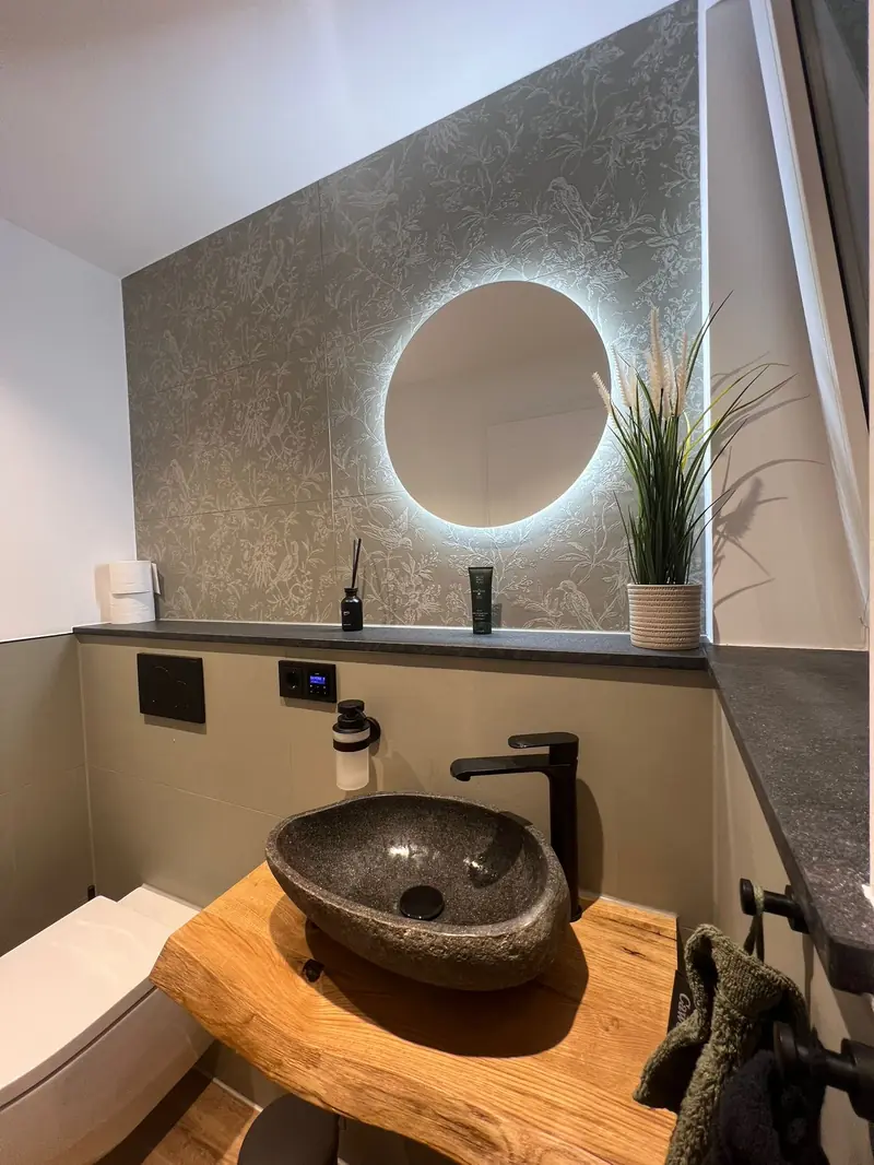 Gäste-WC mit Steinwaschbecken auf Holzplatte und Fensterbank aus dunklem Naturstein
