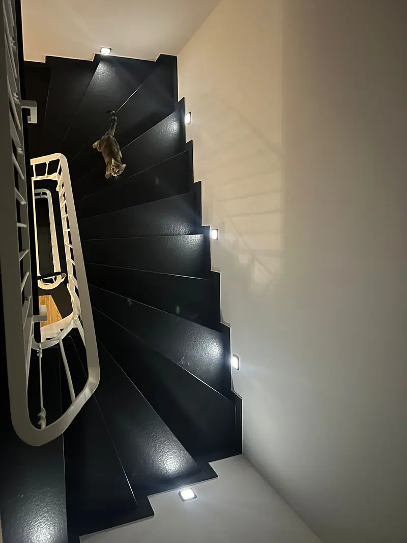 Schwarze Treppe mit Naturstein-Stufen von oben, mit LED-Beleuchtung